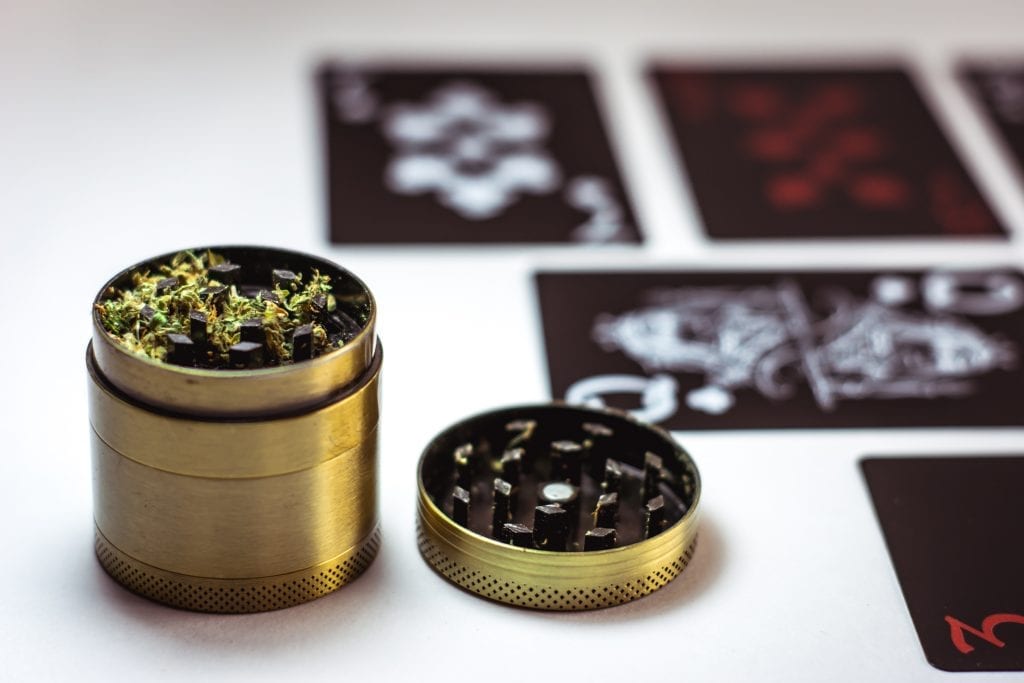 cannabis grinder with grinded cannabis inside on table with stickers