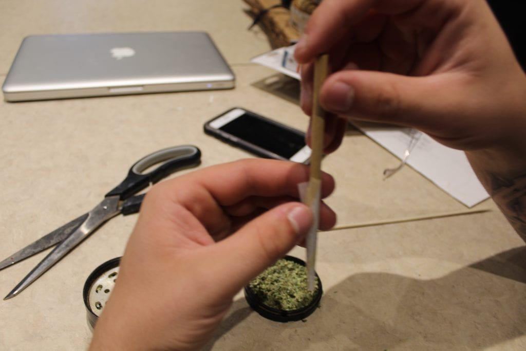 pre-rolled joint being packed down and filed with cannabis. 