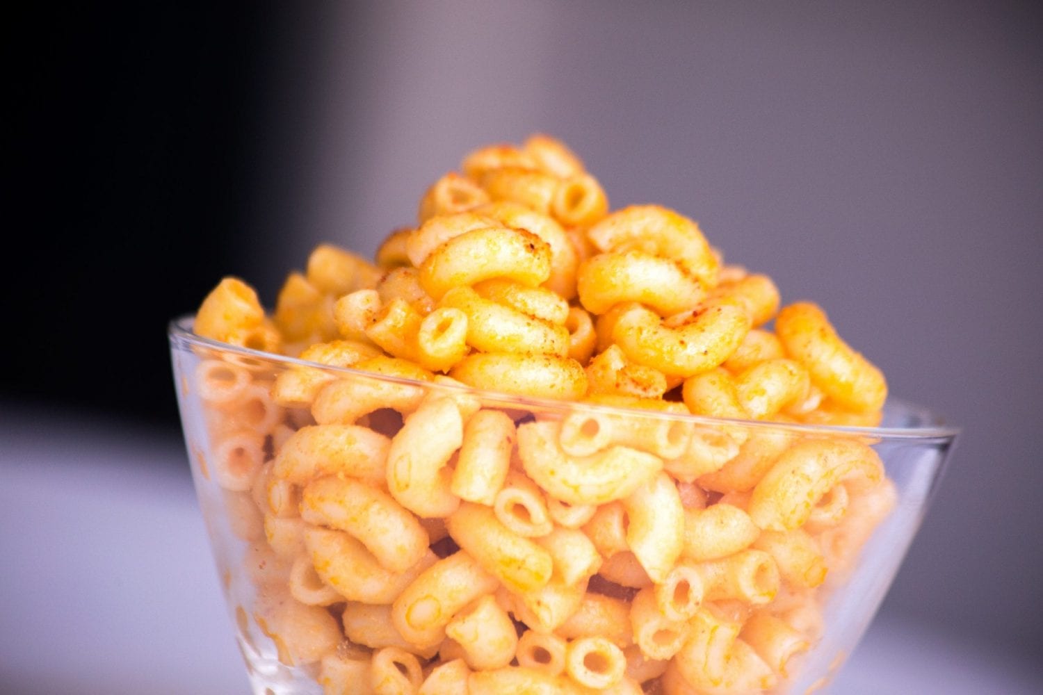 Cannabis infused macaroni and cheese on a white table in a clear bowl.