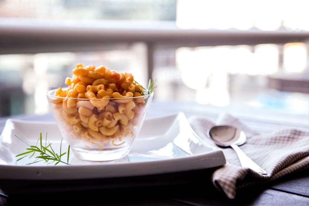 weed mac n cheese on a white plate. Fork on a serviette on a balcony. 