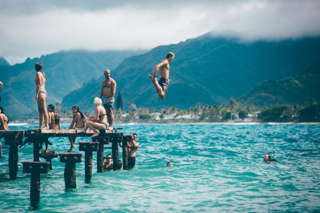 Activities to do high with your friends. Blue water with friends jumping off the dock. 