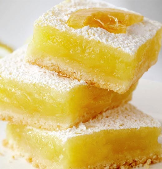 Infused lemon squares stacked on top of each other with a white background