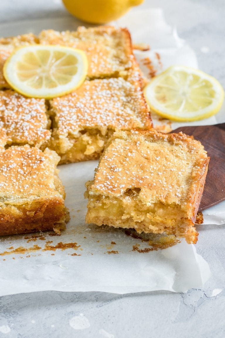 Cannabis infused emon squares with sliced lemons on top of them. The squares are spread on a baking tray