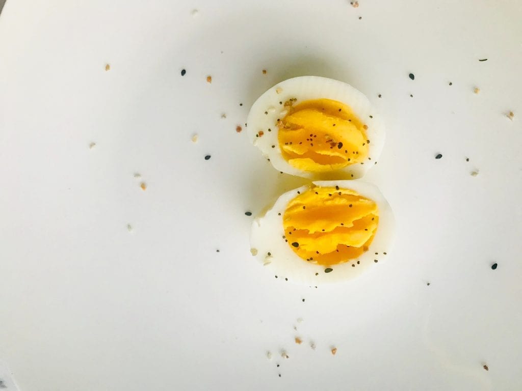 2 weed infused devilled eggs on a white backdrop. Salt, pepper, and other spices on the eggs and the table