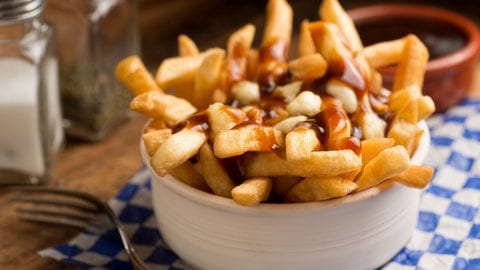 close up image of cannabis infused poutine on blue checkered tablecloth with a fork beside it and salt and pepper beside them