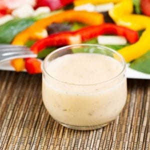 cannabis infused salad dressing in a cup with salad and a fork in the background