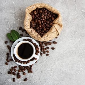 cup of weed coffee laying beside coffee beans.