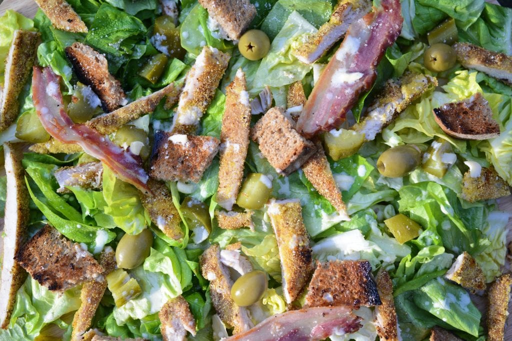 macro shot of cannabis infused salad with bacon, olives, green peppers, and cannabis salad dressing