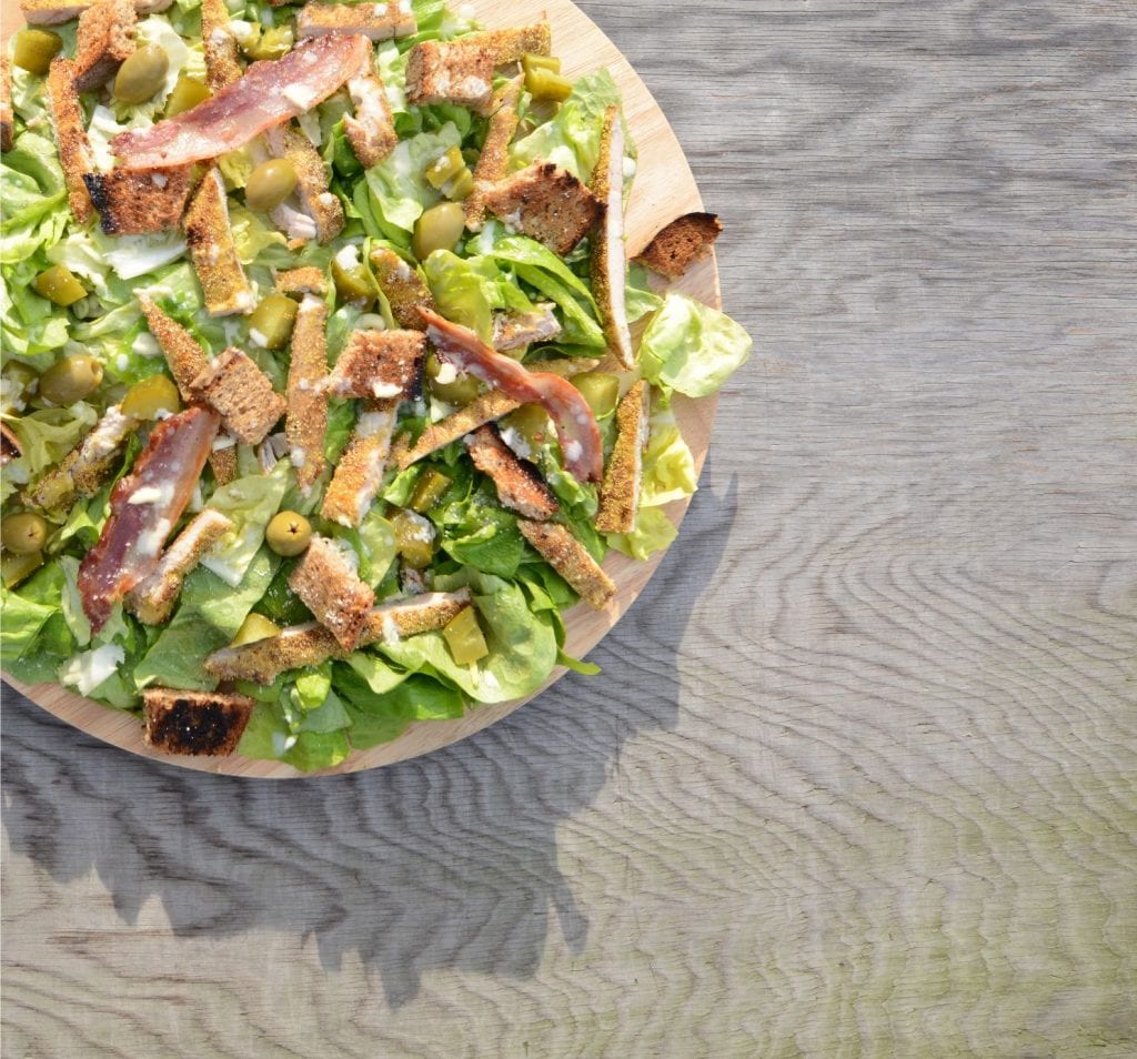 weed infused salad on a wooden cutting board on a wooden countertop. A fancy weed edible side dish.