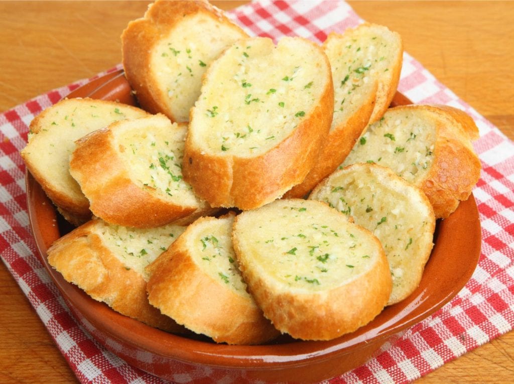 a bowl of cannabis infused garlic bread on a kitchen towel on a wooden surface. A fancy weed edible side dish.