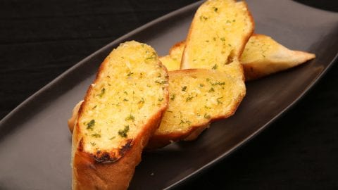 slices of weed garlic bread on a black abstract plate