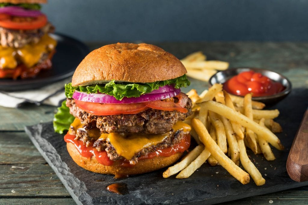 grey plate with french fries and a weed burger with another edible burger in the background. A weed edible dinner recipe.