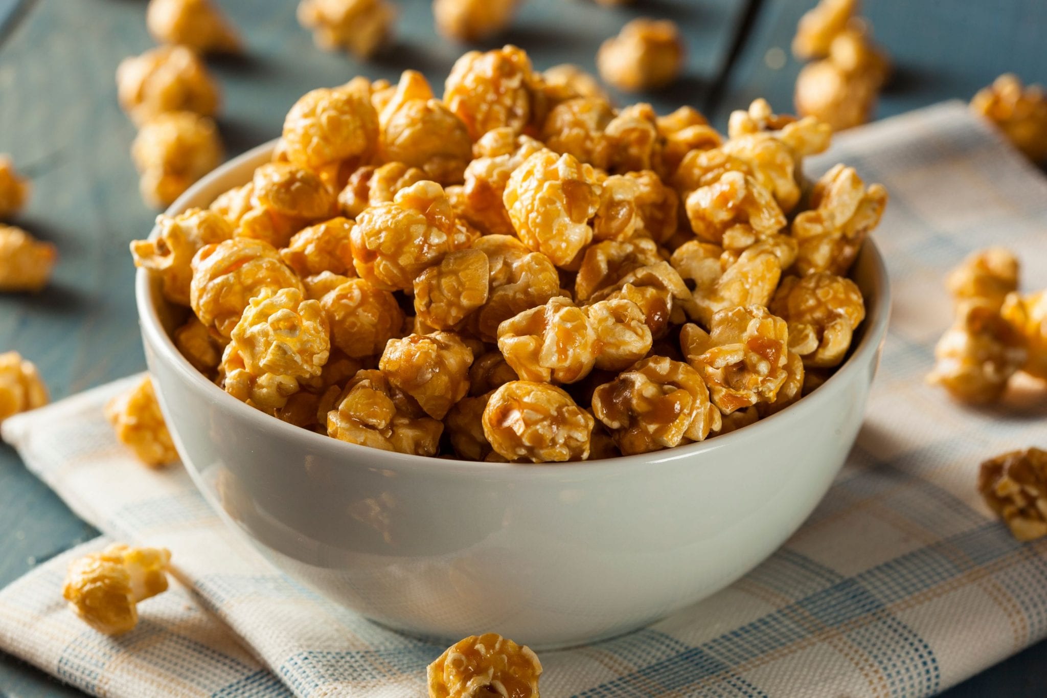 bowl of caramel cannabis popcorn on a napkin with more popcorn spread around on the surface