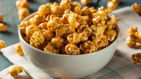 bowl of caramel cannabis popcorn on a napkin with more popcorn spread around on the surface