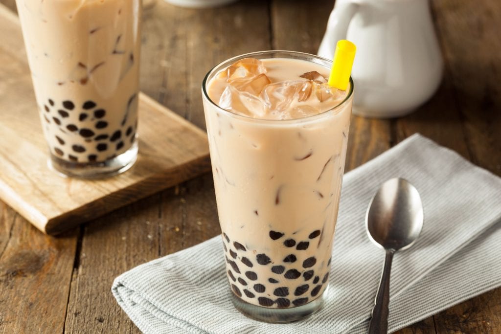 weed infused bubble tea on a napkin with a spoon beside it. Wooden cutting board in the background with more weed bubble tea in the background