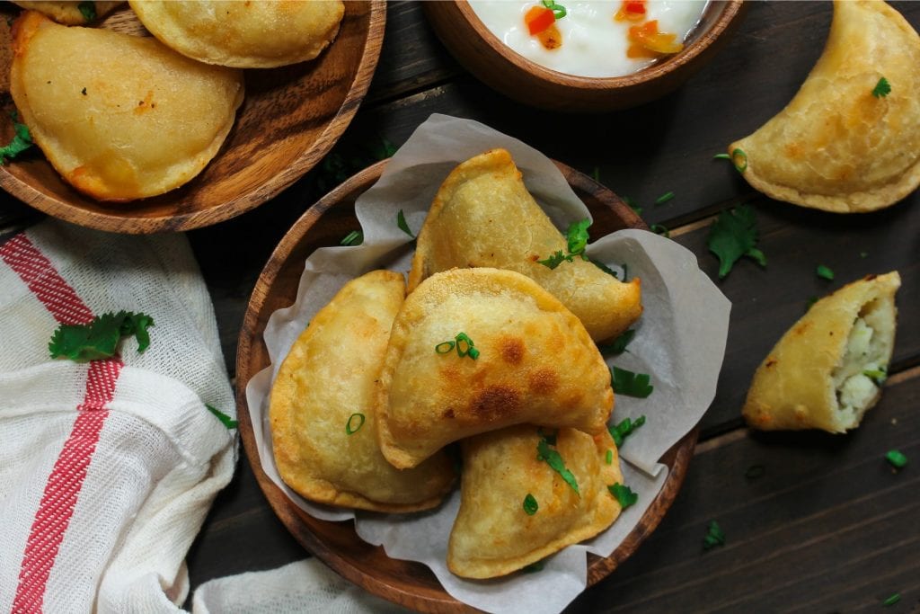 overhead shot of cannabis infused perogies with sour cream and more perogies in the background