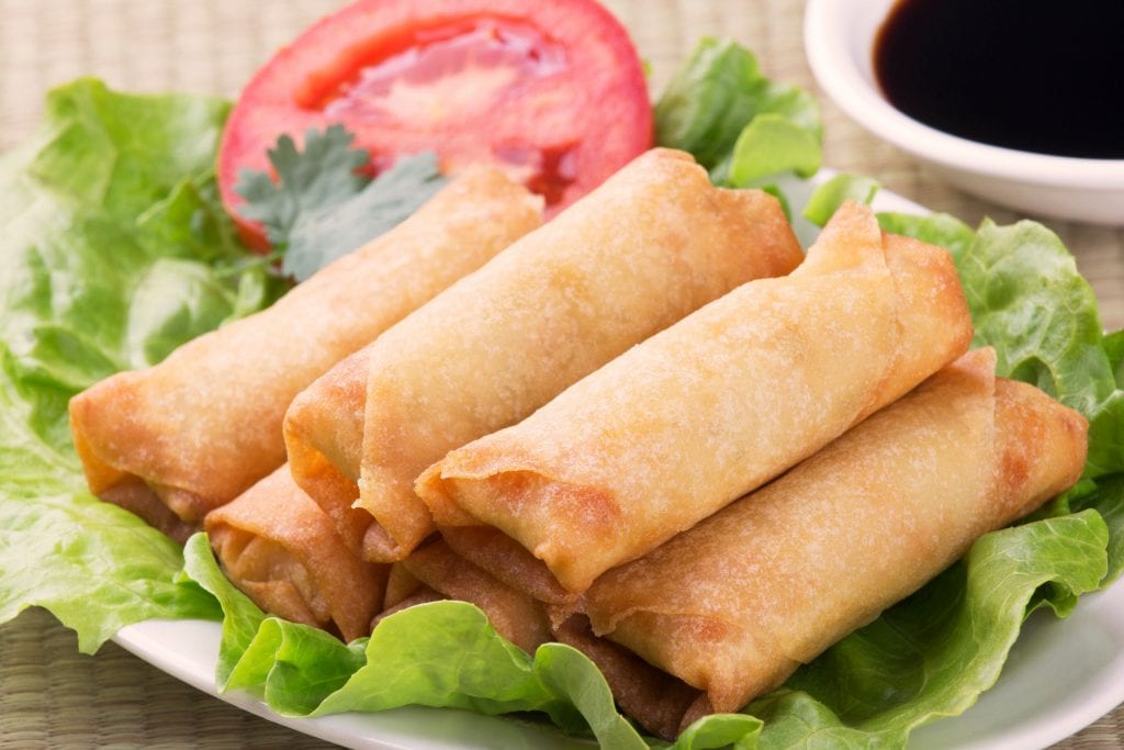 Six weed spring rolls on a piece of lettuce and tomato on a white plate