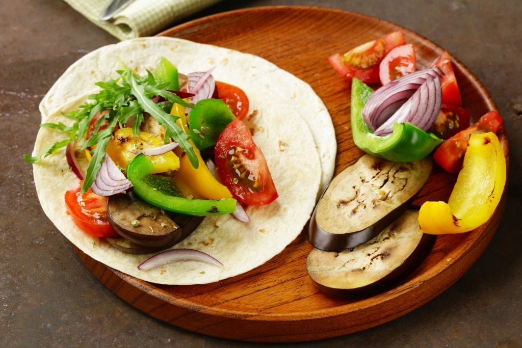 Cannabis infused fajitas With veggies besides them on a wooden plate