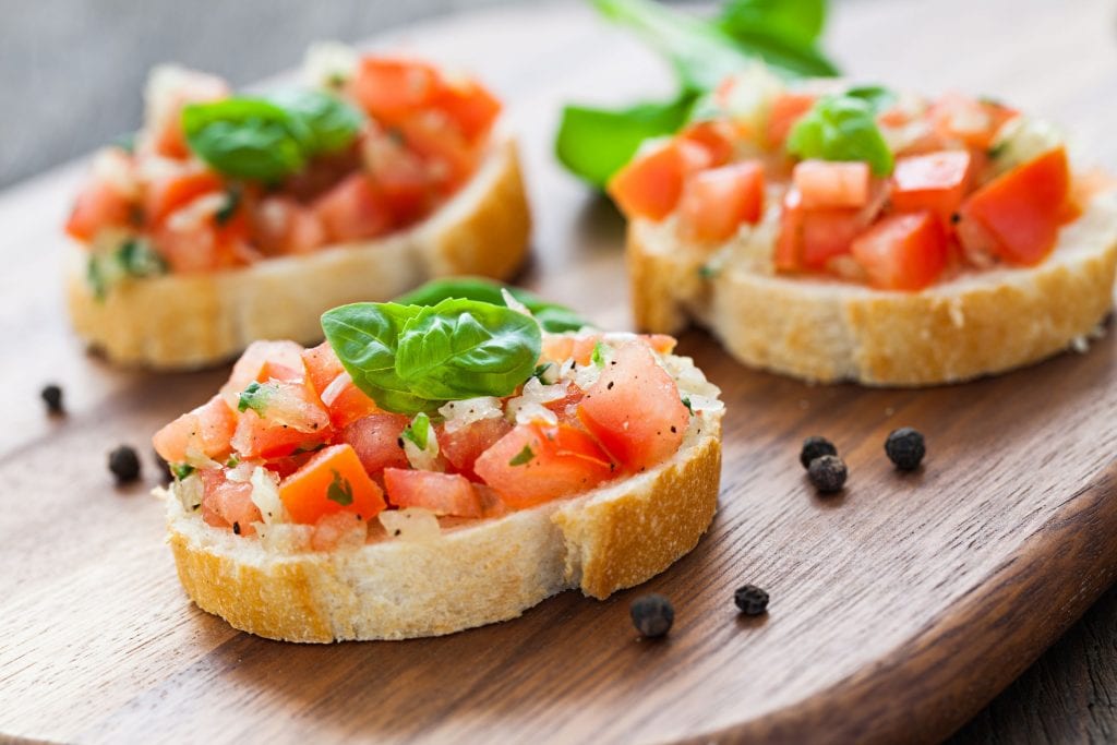 weed infused bruschetta with peppercorn beside them on a wooden cutting board