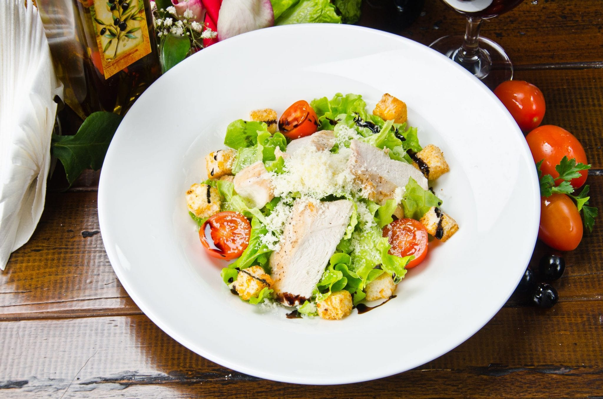 fresh cannabis infused caeser salad with parmesan cheese and a glass of wine in the background