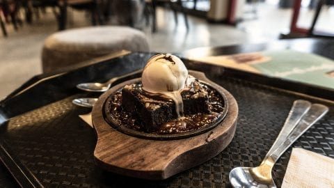 Cannabis infused chocolate lava cake with a scoop of ice cream on top of it and all of this is on a wooden plate