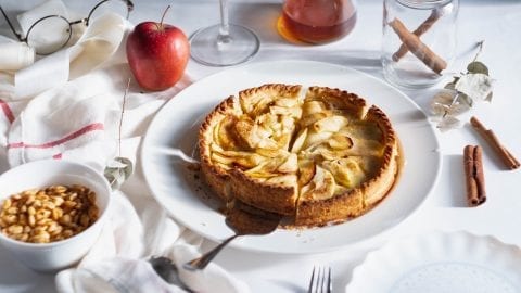 Cannabis apple pie.On a white table with a pie cutter taking a slice out of it and peanuts cinnamon and apple and other decorative items in the background