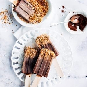 Chocolate Popsicles infused with cannabis on a white table with sprinkles and chocolate powder beside it