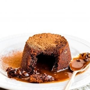 Cannabis infused lava cake on a white plate With a spoon for sale on the plate the lava cake has been cut open and is spilling onto the plate with brown powder in the back