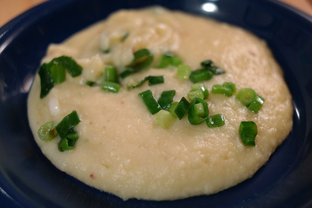 Edible potato soup on a blue plate garnish with green onion