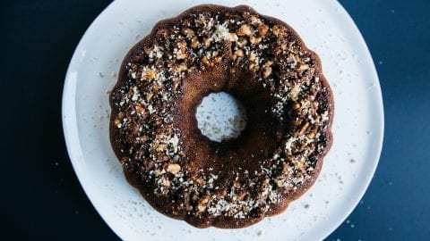 Overhead shot of cannabis infused coffee cake on a white plate with crumbs spread over the plate and all of this is on a blue table