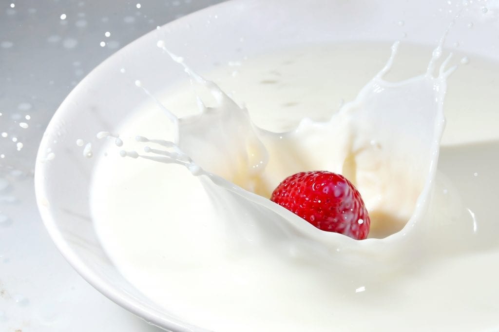 Strawberry being dropped into a glass of milk