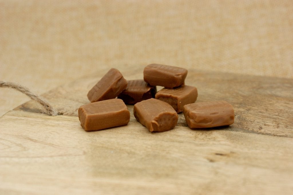 Infused caramel cubes on a brown wooden table shot in macro