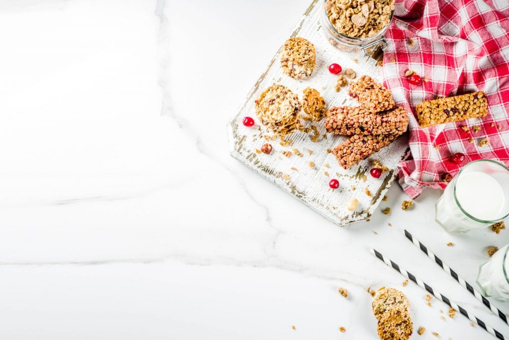 Multi grain cannabis edible granola muesli bar. Healthy sweet food, diet snack, with dried berries, nuts, cereals and honey on a white marble background