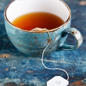 Edible tea in a blue tea cup on a blue counter surface.