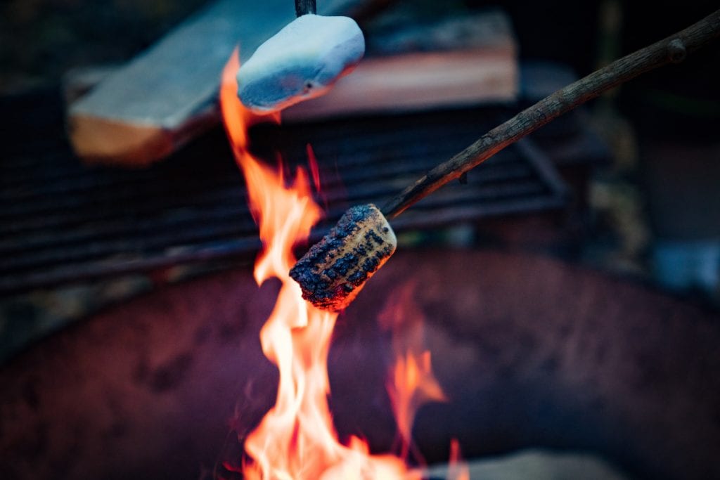 people roasting cannabis infused marshmallows outdoors over an open fire