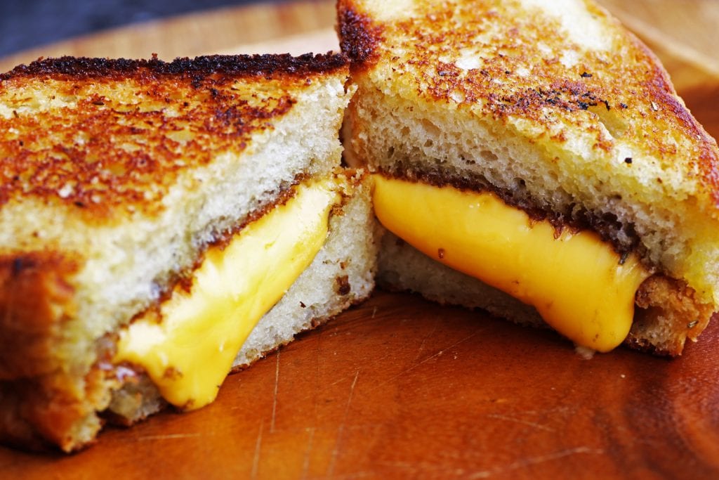 weed Grilled cheese sandwich on wood platter with rosemary bread & melted cheddar cheese