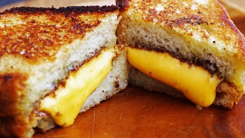 weed Grilled cheese sandwich on wood platter with rosemary bread & melted cheddar cheese