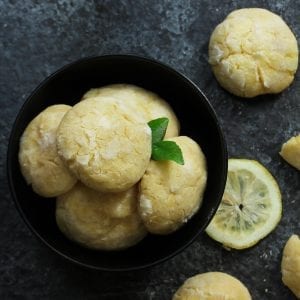 overhead shot of cannabis infused lemon cookies in a black bowl with more cookies spread around on the table