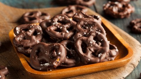 Homemade weed Chocolate Covered Pretzels with Sea Salt on a wooden platter which is all on a rustic wooden cutting board