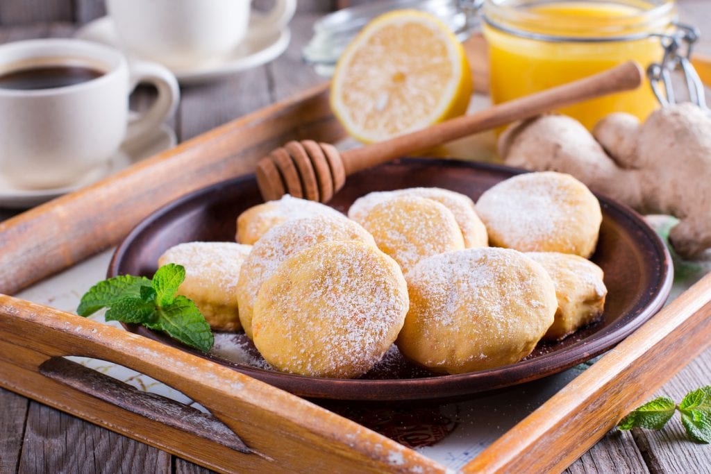 homemade cannabis infused lemon cookies on a bron plate with lemon in the background and cups of coffee