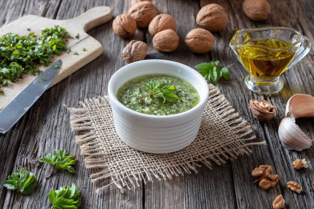 a image of weed pesto from the side. The parsley sits on top with chopped onions on either side.