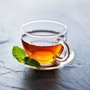 glass of hot weed tea with mint garnish