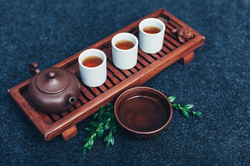 Traditional weed tea ceremony accessories. # glasses of cannabis tea on a wooden board with a clay pot beside them.