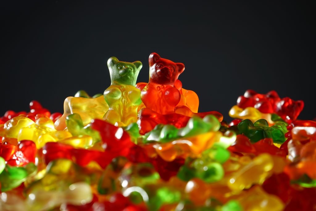 CBD infused gummy bears sit in a big pile on top of each other. The gummy bears are red, yellow, and green in color.