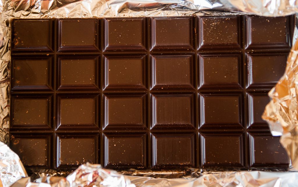 CBD chocolate bar in a tinfoil wrapper. The chocolate bar is divided into 24 portions. 