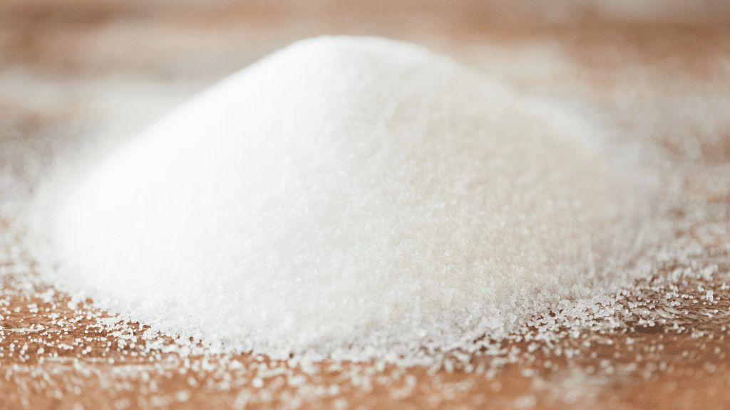 a pile of white cbd sugar that forms a small pyramid shape. The pile sits on a wooden surface.